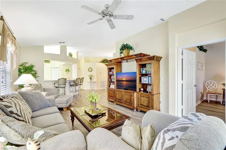 Living room with wood finished floors, ceiling fan, and vaulted ceiling