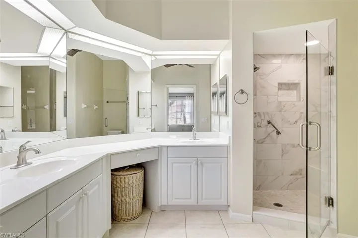 Bathroom featuring double vanity, a stall shower, and light tile patterned floors