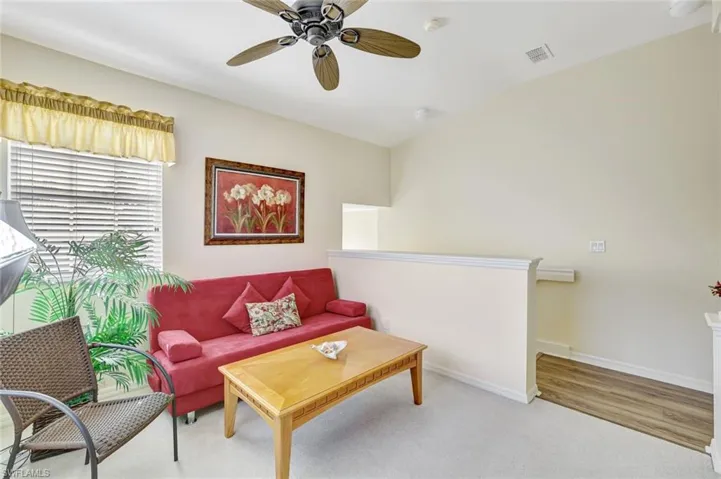 Carpeted living room featuring ceiling fan and baseboards