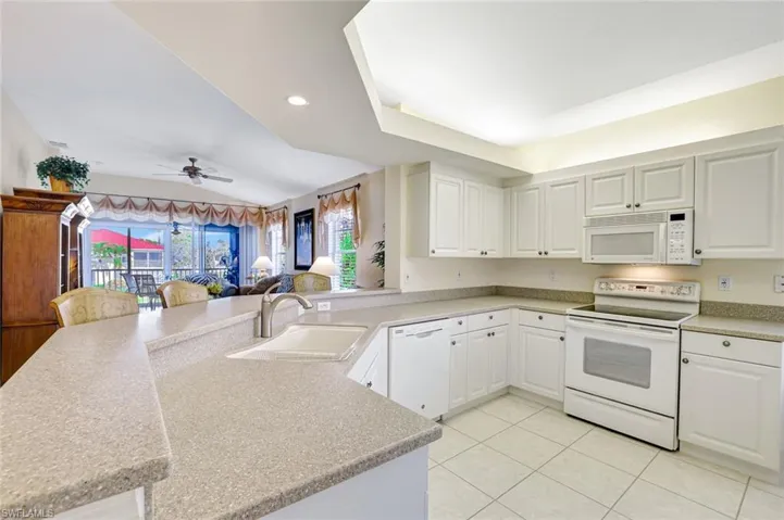 Kitchen featuring white appliances, a peninsula, white cabinetry, open floor plan, and recessed lighting