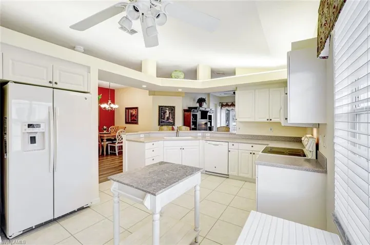 Kitchen featuring white appliances, white cabinetry, a peninsula, and light tile patterned floors