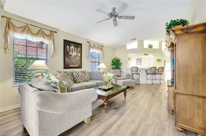Living area with vaulted ceiling, light wood-style floors, and a ceiling fan