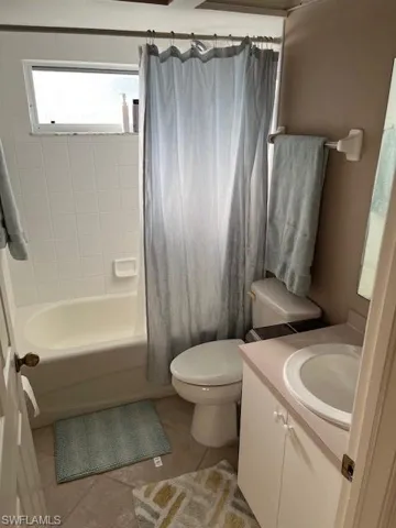 Full bathroom featuring vanity, toilet, tile patterned floors, and shower / tub combo with curtain
