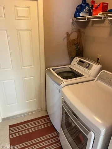 Clothes washing area featuring washer and dryer and light tile patterned floors