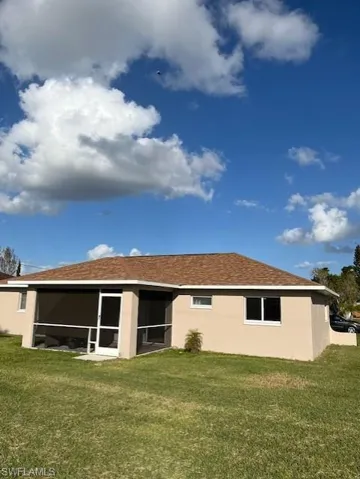Back of house with a yard and a sunroom