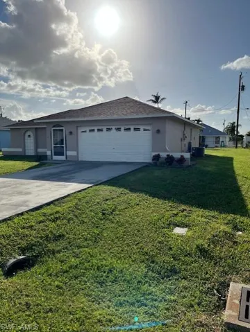 Ranch-style house featuring a front yard, central AC, and a garage