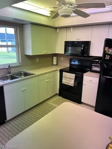 Kitchen featuring sink, black appliances, and white cabinets