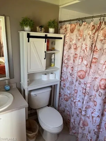 Bathroom with vanity, curtained shower, toilet, and tile patterned floors
