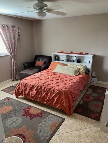 Bedroom with ceiling fan and light tile patterned floors