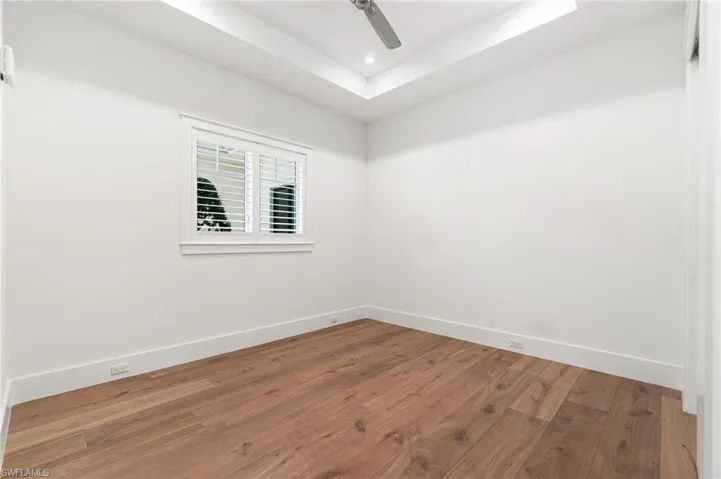 Empty room featuring a tray ceiling, hardwood / wood-style floors, and ceiling fan