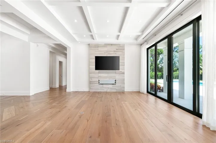 Unfurnished living room featuring french doors, beam ceiling, tile walls, and coffered ceiling