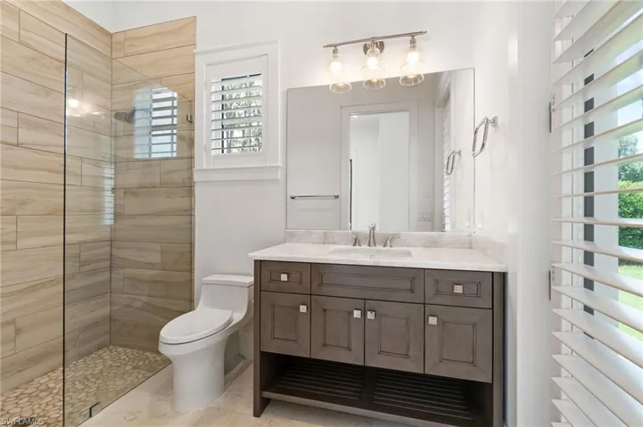 Bathroom with vanity, tile patterned flooring, a tile shower, and toilet