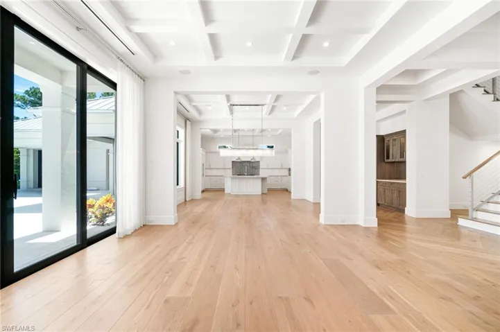 Unfurnished living room featuring beamed ceiling, light hardwood / wood-style flooring, and coffered ceiling