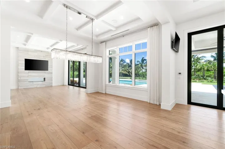 Unfurnished living room with light hardwood / wood-style flooring, coffered ceiling, french doors, and tile walls
