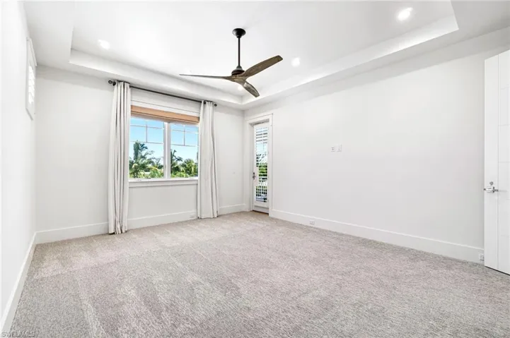 Unfurnished room with light carpet, ceiling fan, and a raised ceiling