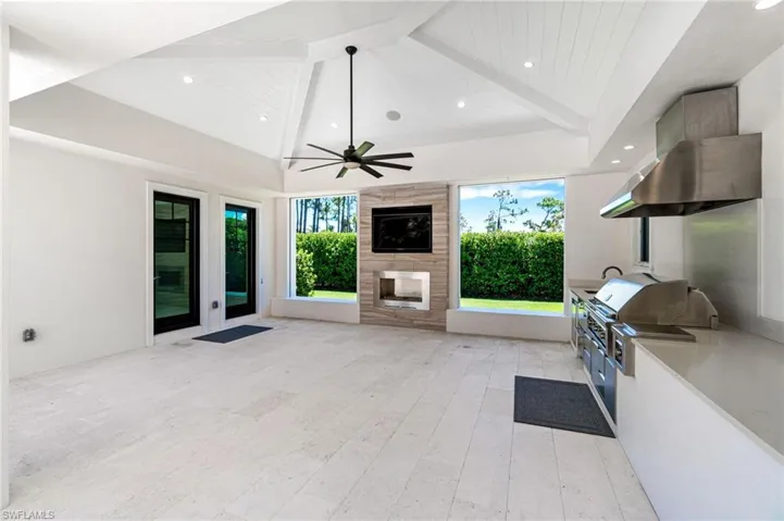 Unfurnished living room with lofted ceiling with beams, ceiling fan, a large fireplace, and light hardwood / wood-style floors