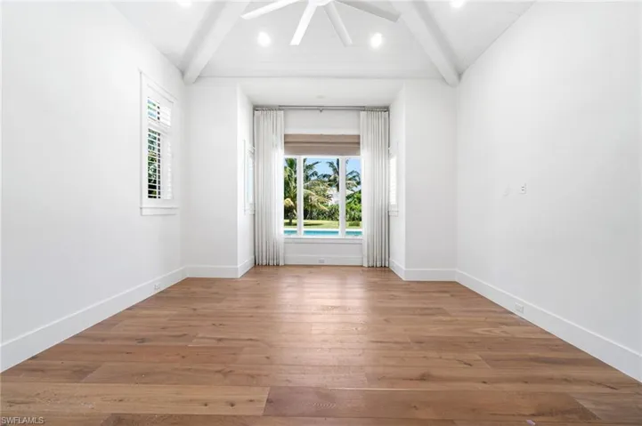 Unfurnished room with vaulted ceiling with beams, ceiling fan, and wood-type flooring