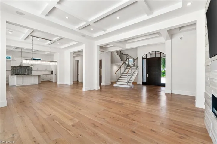 Unfurnished living room with light hardwood / wood-style floors, beam ceiling, and coffered ceiling