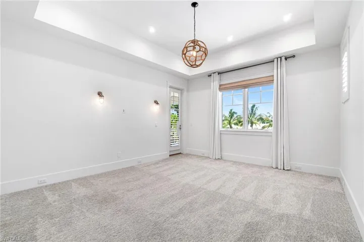 Unfurnished room with light carpet and a tray ceiling