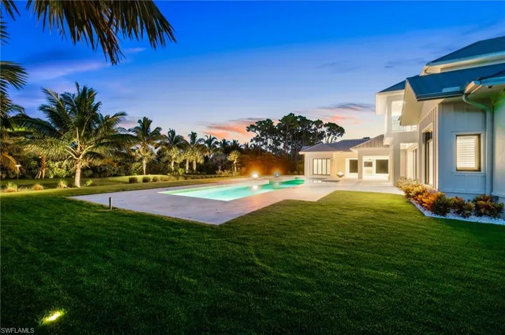 Pool at dusk with a patio and a lawn