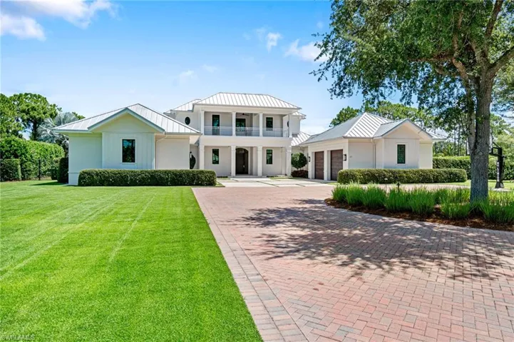 View of front of property featuring a garage, a balcony, and a front lawn