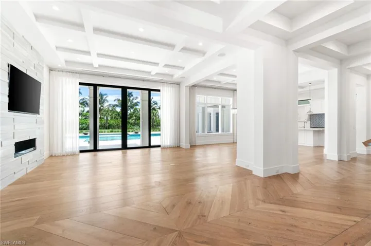 Unfurnished living room with beamed ceiling, a fireplace, french doors, light parquet floors, and coffered ceiling