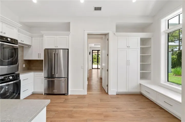 Kitchen featuring white cabinets, light hardwood / wood-style floors, high end refrigerator, and tasteful backsplash