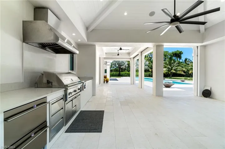 Kitchen featuring plenty of natural light, wall chimney exhaust hood, light tile patterned floors, and ceiling fan