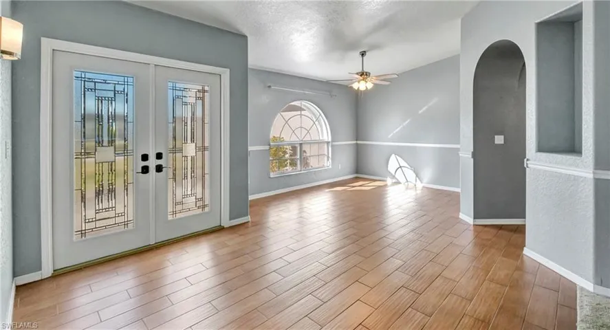 Entryway with arched walkways, wood finish floors, french doors, a textured ceiling, and a ceiling fan