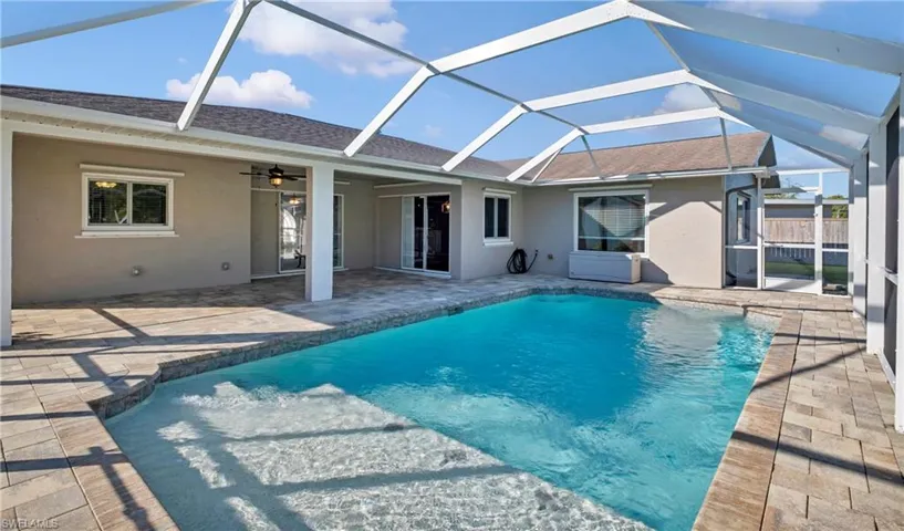 Outdoor pool featuring a sunroom, glass enclosure, and a patio area