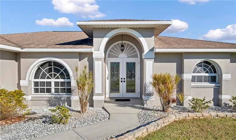 Entrance to property featuring french doors, roof with shingles, and stucco siding