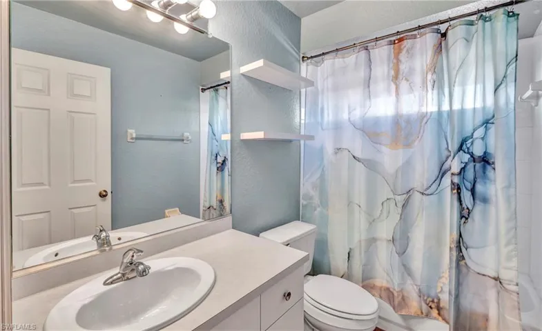 Bathroom with a textured wall, shower / bath combo, and vanity