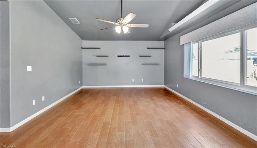 Empty room with light wood-type flooring, vaulted ceiling, and ceiling fan