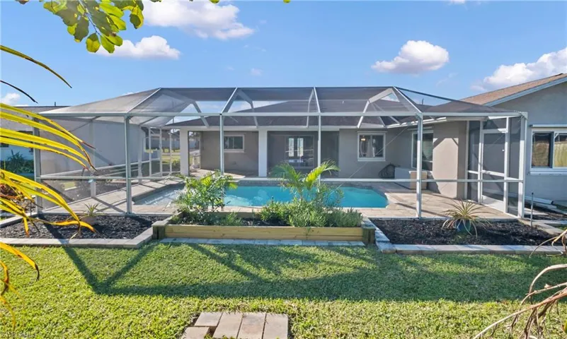 Rear view of property featuring a lanai, a sunroom, stucco siding, and a yard