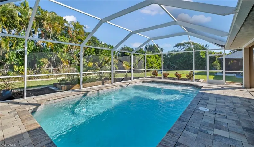 Swimming pool with glass enclosure, a sunroom, and a patio area
