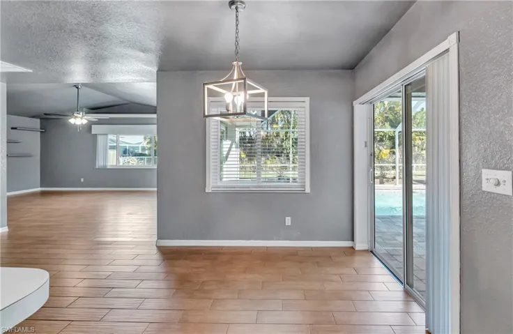 Unfurnished dining area featuring wood finish floors, a textured wall, a ceiling fan, and a textured ceiling