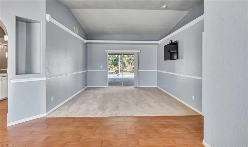Spare room with a textured wall, wood tiled floors, and vaulted ceiling