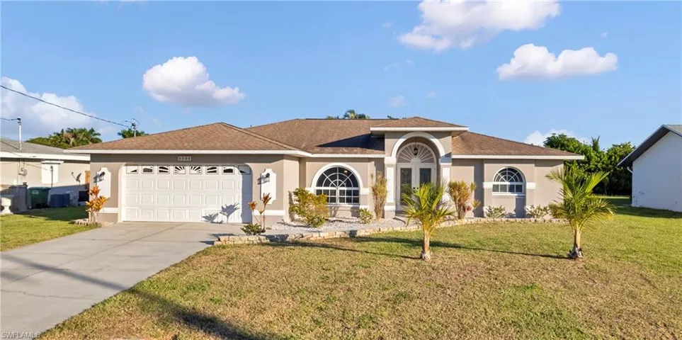View of front of property with stucco siding, a front lawn, driveway, roof with shingles, and a garage