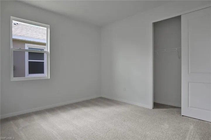 Unfurnished bedroom featuring light carpet and a closet