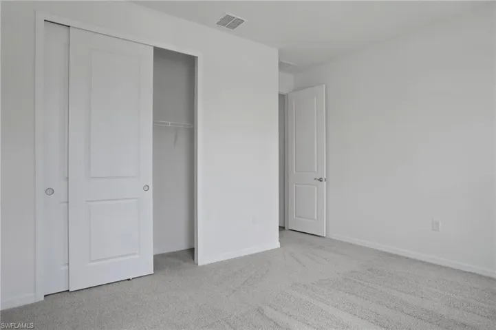 Unfurnished bedroom with light colored carpet and a closet