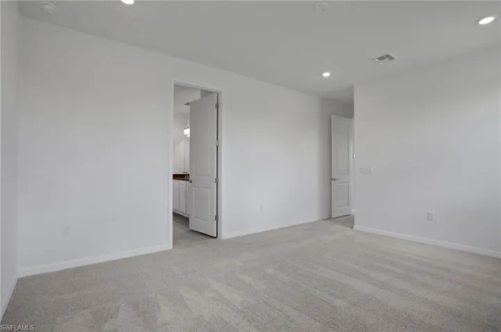 Empty room with light colored carpet and recessed lighting