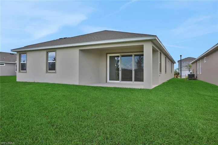 Rear view of house featuring a patio area, stucco siding, and a yard