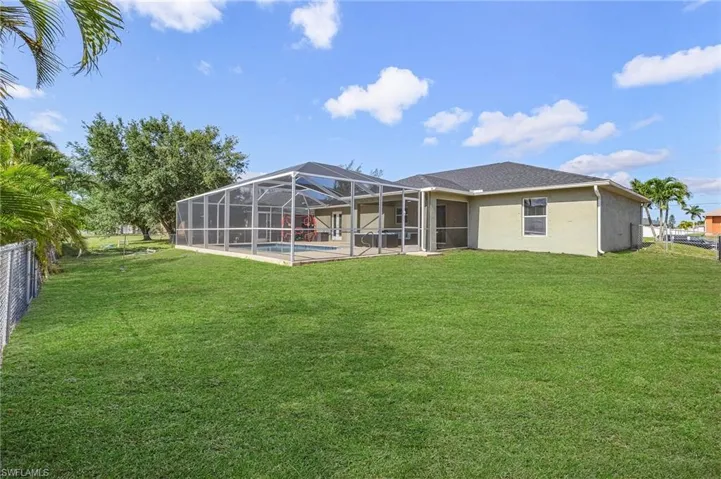 Back of house featuring an outdoor pool, stucco siding, glass enclosure, and a patio