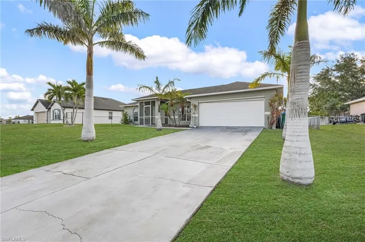 Single story home featuring concrete driveway, a garage, a front yard, and stucco siding