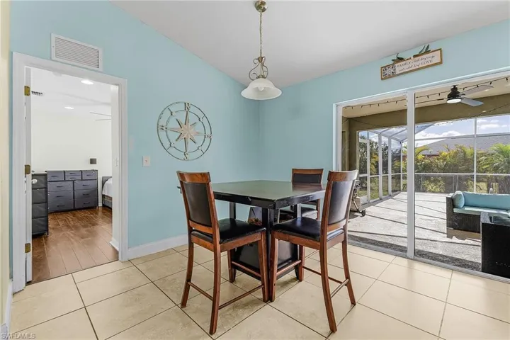 Dining room with ceiling fan, light tile patterned floors, baseboards, and vaulted ceiling