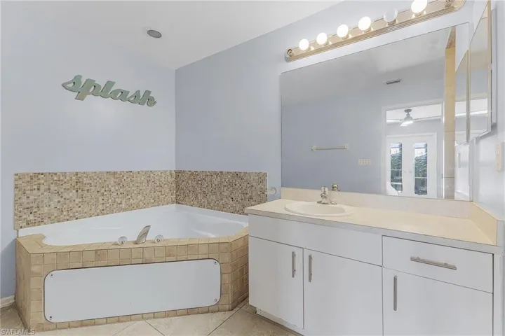 Bathroom featuring tile patterned floors, a bath, vanity, and a ceiling fan