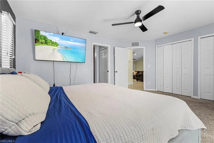 Carpeted bedroom with two closets, a ceiling fan, and baseboards