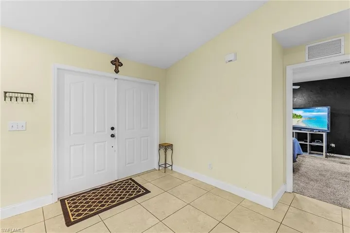 Foyer with light tile patterned floors and baseboards