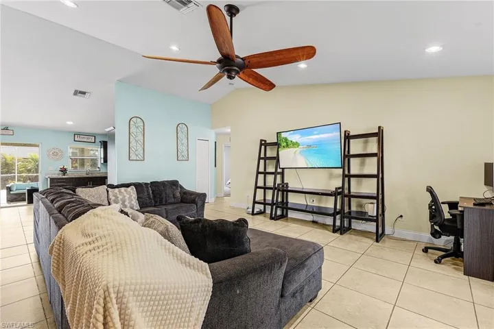 Living area featuring light tile patterned flooring, vaulted ceiling, an office area, a ceiling fan, and recessed lighting