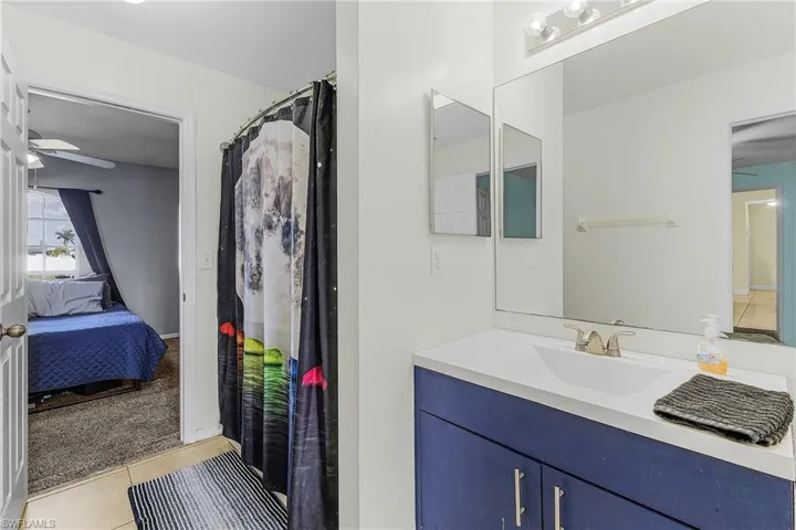 Bathroom featuring a ceiling fan, ensuite bathroom, tile patterned floors, and vanity